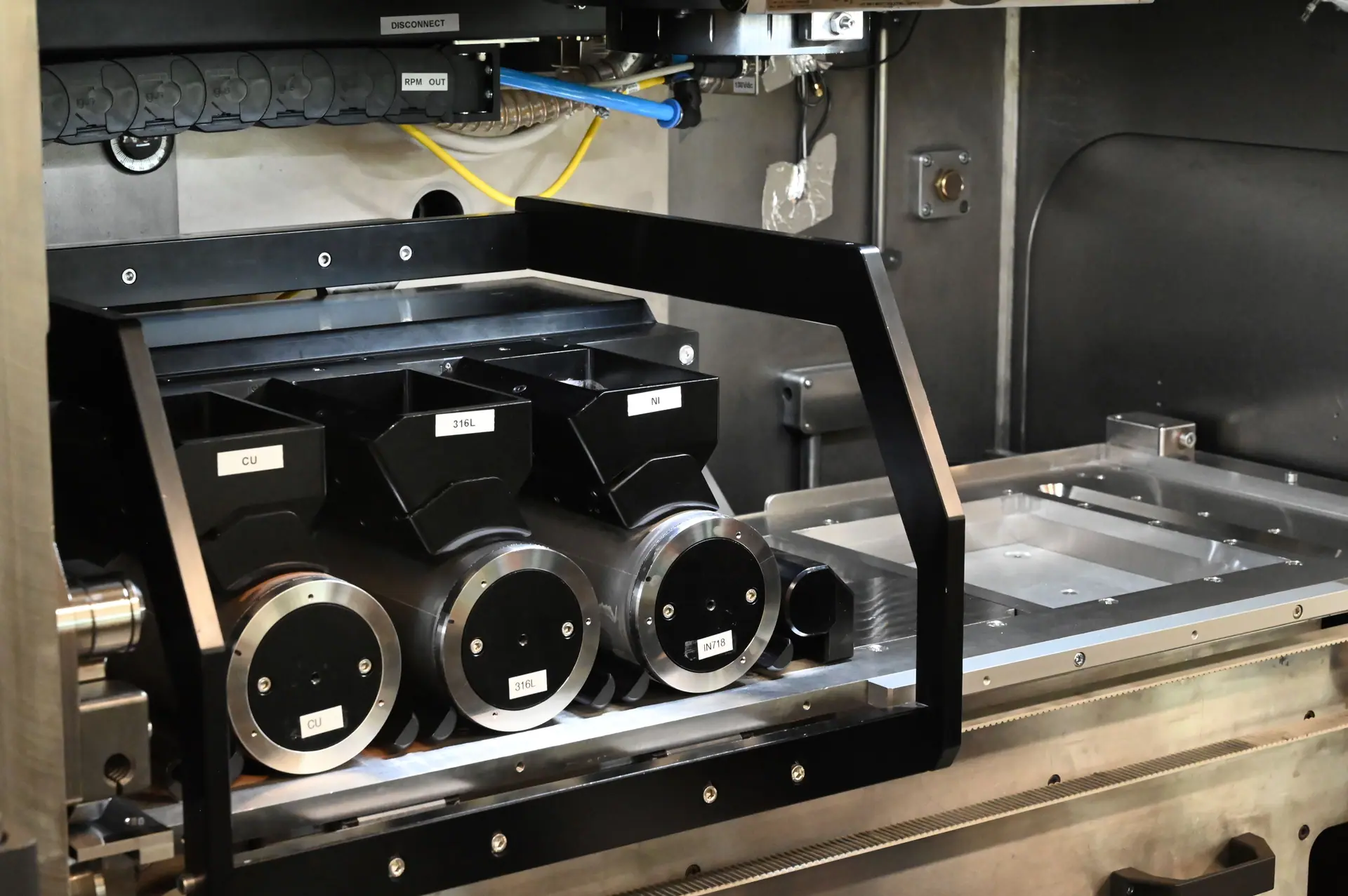 Multi-material powder feed heads — copper, 316L and nickel — inside a large-format print chamber.